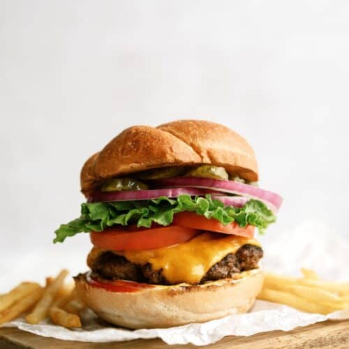 Classic Burger on a cutting board with some French fries.