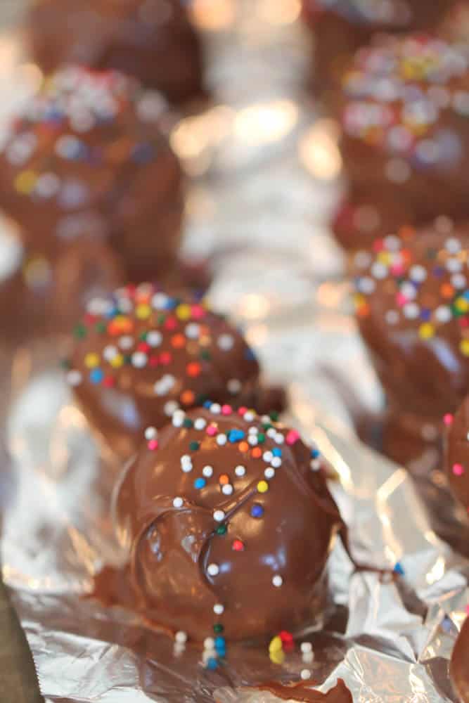 Reese's Nutter Butter Cookie Truffles topped with sprinkles, lined up on a baking sheet.