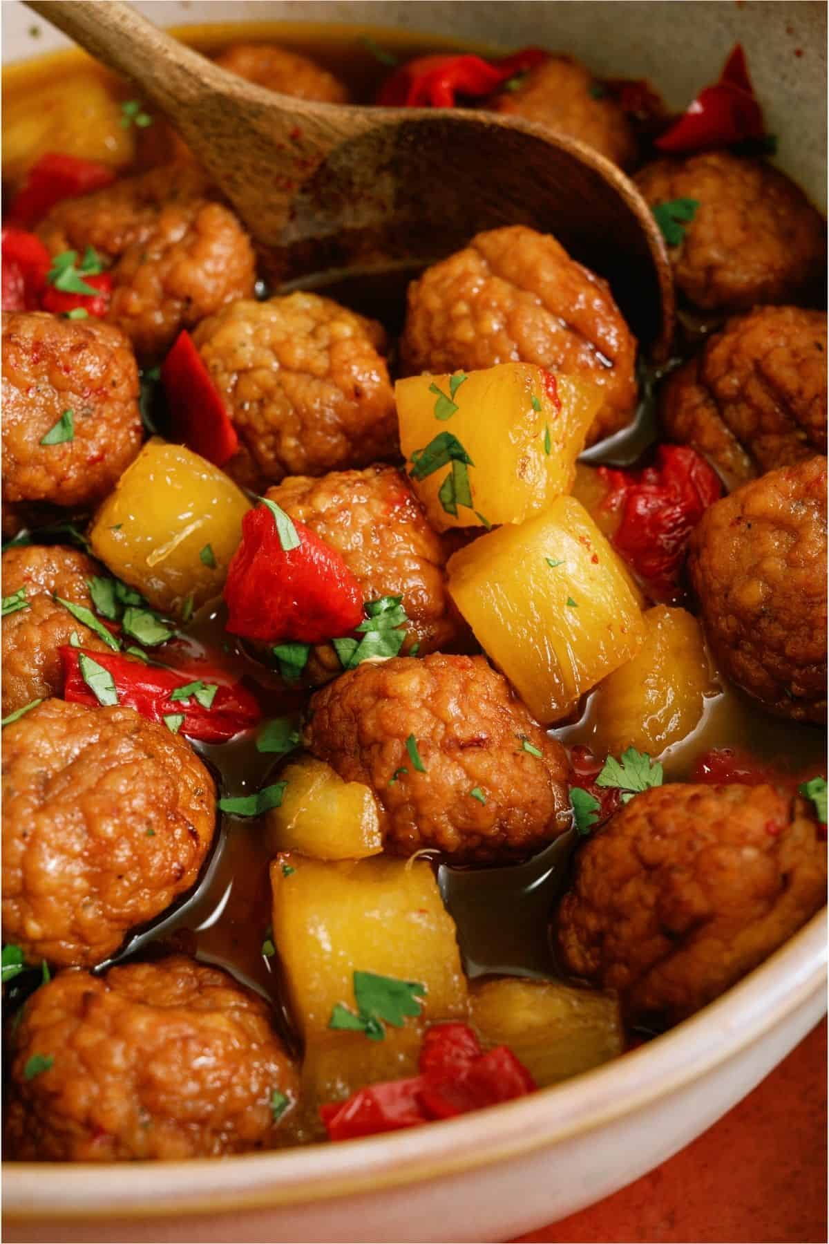 Instant Pot Hawaiian Meatballs in a serving dish with a wooden spoon.